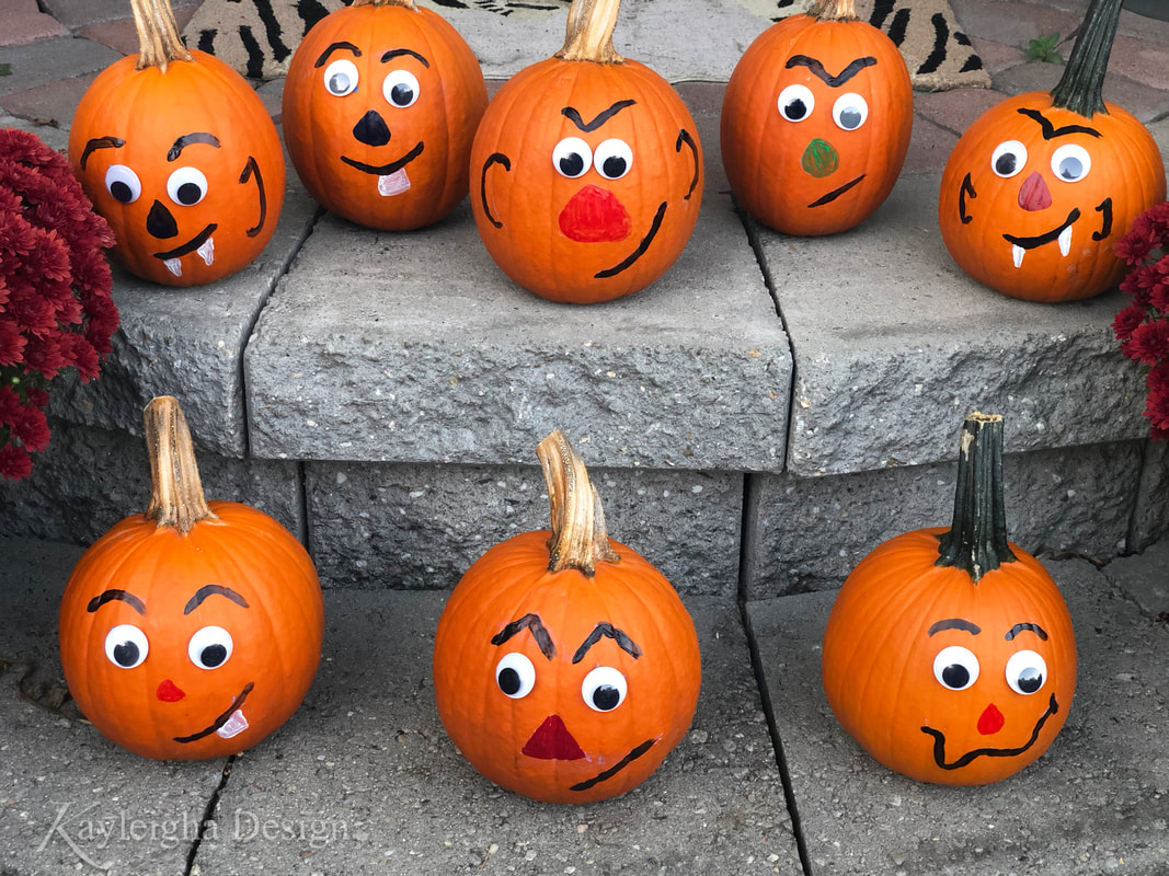 Small pumpkins with googley eyes and silly faces sitting on stone porch steps.