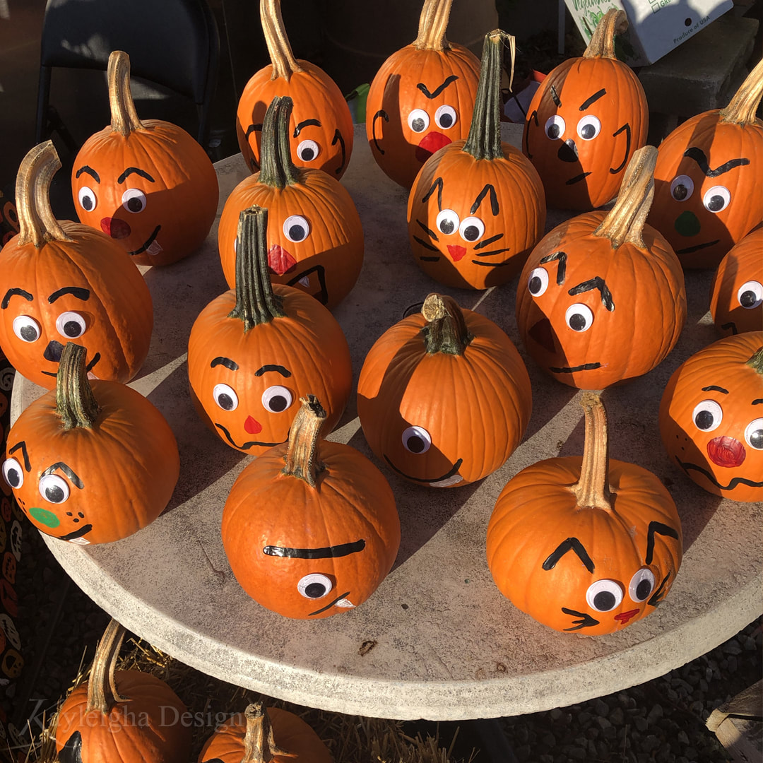 A table covered in small pumpkins with googley eyes and silly faces.